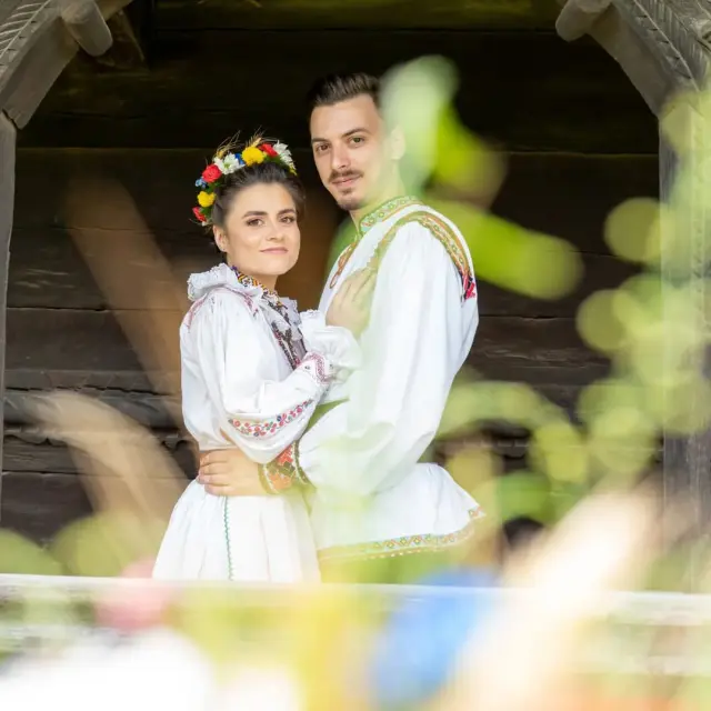 Während ihrer Trash the Dress-Fotosession im Freien in Cluj-Napoca trägt das Brautpaar rustikale rumänische Trachten, umgeben von Natur und traditionellen Dorfhäusern.